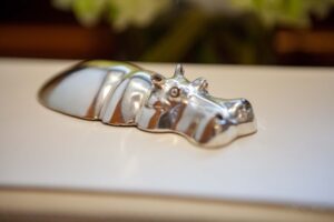 Detail of a small metal sculpture of a hippo seemingly resting on the flat surface of a hard book.